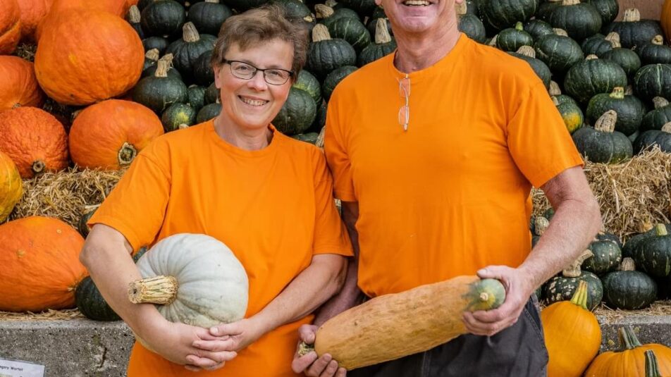 Trudy und Walter Bühlmann vom Bauernhof Bürlimoos in Rothenburg, von denen Bruno seine Kürbisse für die Saisonspezialität «Kürbis & Marroni» bezieht, posieren vor frischen Kürbissen.