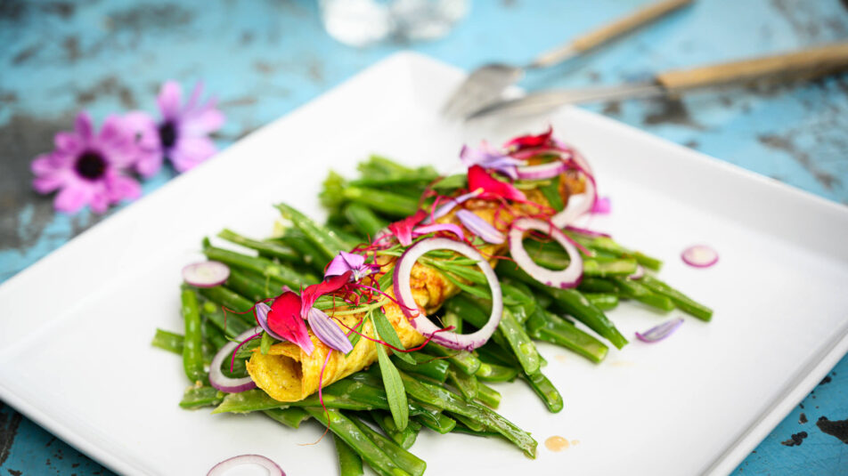 Bohnensalat mit Rührei, angerichtet auf einem weissen Teller.