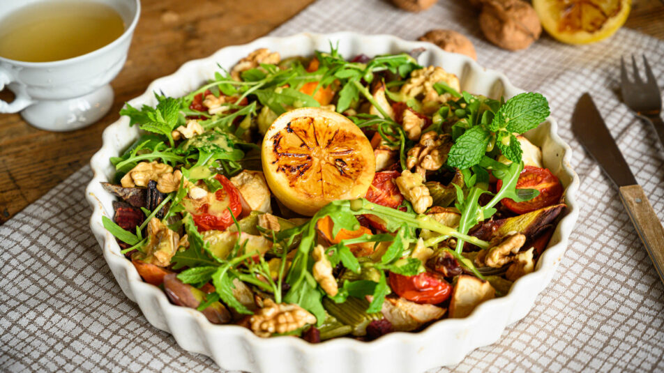 Gratinform mit geschmortem Gemüsesalat, in der Mitte eine flambierte Zitrone.