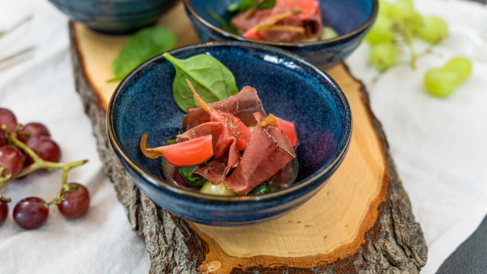 Trauben-Chutney mit Mostbröckli auf einem rustikalen Holzbrett serviert.