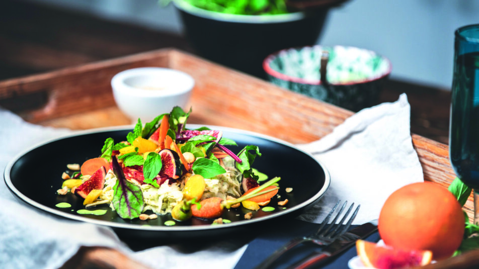 Frühlingshafter Bärlauch-Selleriesalat auf dunklem Teller, auf einem Tablar serviert.