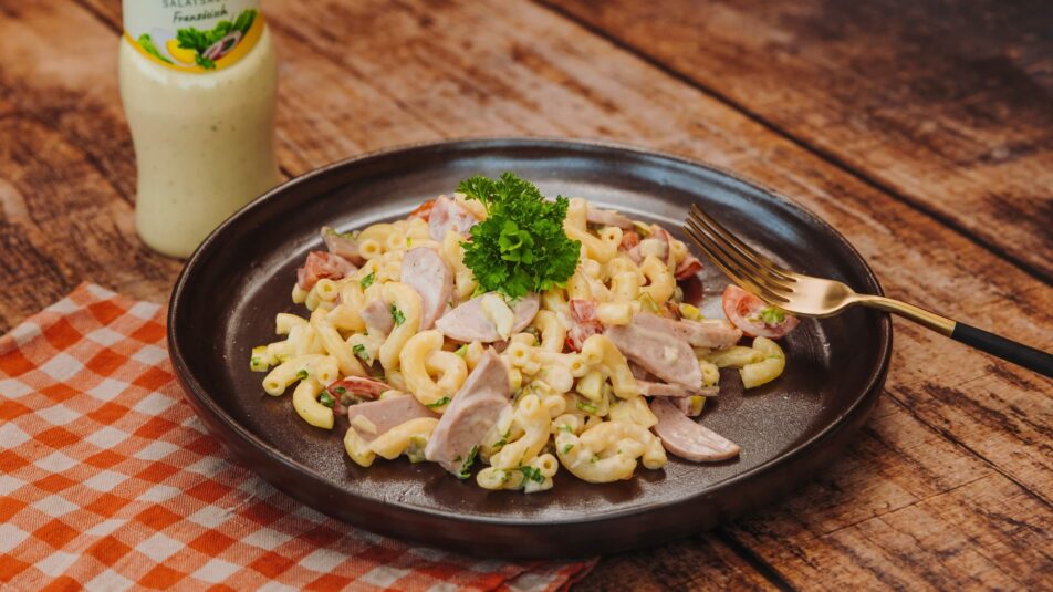 Hörnlisalat mit Cervelat und Cherry-Tomaten, garniert mit frischer Petersilie.