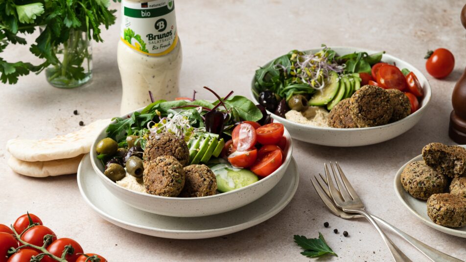Zwei Teller mit Quinoa-Linsen-Taler-Bowl. Im Hintergrund ist eine Flasche Brunos Salatsauce Bio French zu sehen.