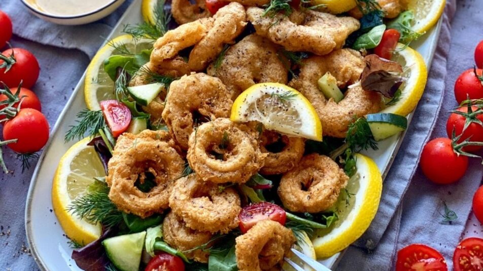 Teller mit veganen Calamari, frischen Zitronen und Cherry-Tomaten.