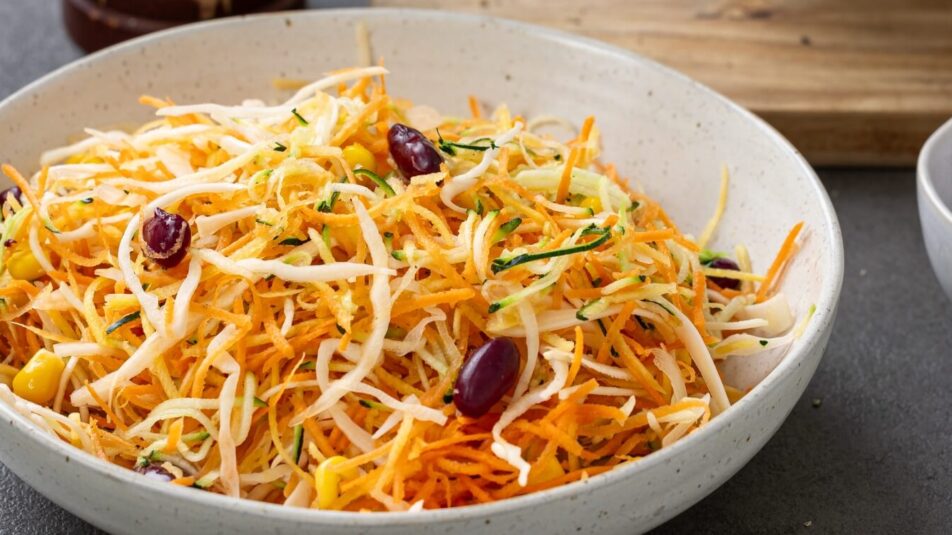 Gemischter Salat mit geraffelten Karotten, Zucchini und Sellerie auf einem Teller angerichtet